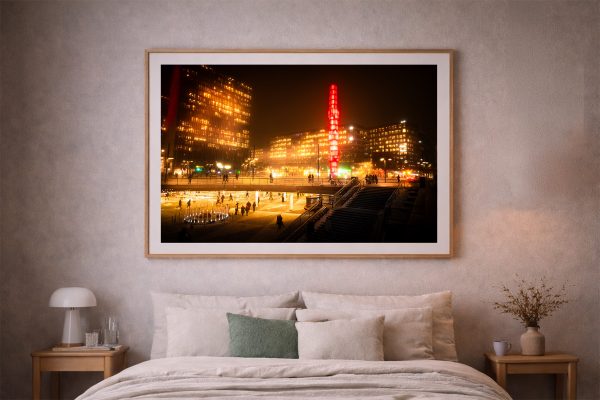 Fotografie eines hell erleuchteten Stadtplatzes bei Nacht mit Menschen, Treppen und Hochhäusern in warmem Licht in einem Schlafzimmer über dem Bett