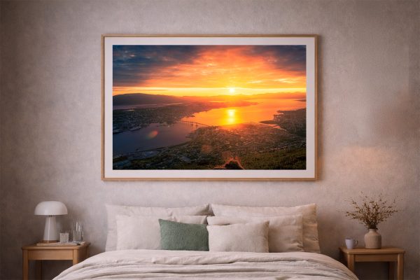 Gerahmtes Panorama-Foto eines leuchtenden Sonnenuntergangs über Küstenstadt und Wasser, über einem Bett im dezenten Schlafzimmer