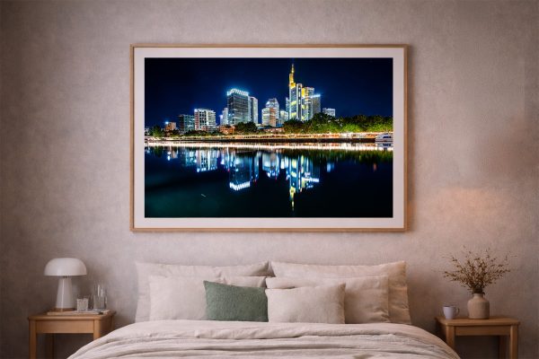 Großformatiges Wandbild einer beleuchteten Skyline mit Spiegelung im ruhigen Fluss über einem gemütlichen Bett im Schlafzimmer