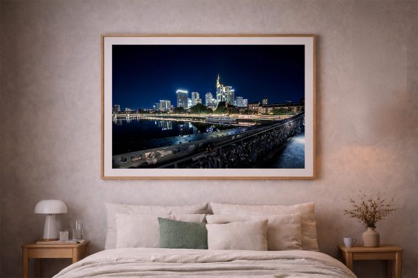 Großer gerahmter Fotoabzug einer hell erleuchteten Skyline bei Nacht mit Fluss und Brücke über einem Bett in einem gemütlichen Schlafzimmer