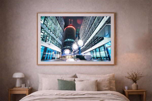Fotografie eines modernen Hochhauses bei Nacht zwischen Glasfassaden, als gerahmtes Wandbild über einem Bett im Schlafzimmer