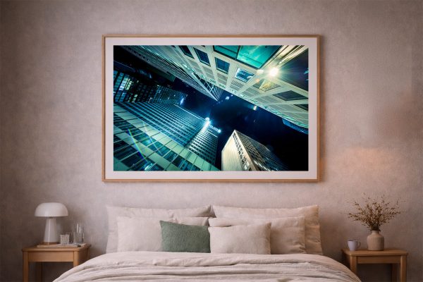 Fotografie von beleuchteten Hochhäusern bei Nacht im Holzrahmen über einem gemütlichen Bett im Schlafzimmer