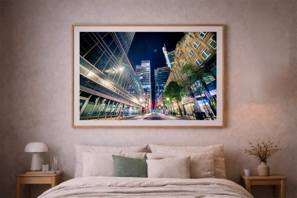Fotografie einer leeren Großstadtstraße bei Nacht zwischen modernen Glasfassaden und älteren Häusern über einem Bett im Schlafzimmer