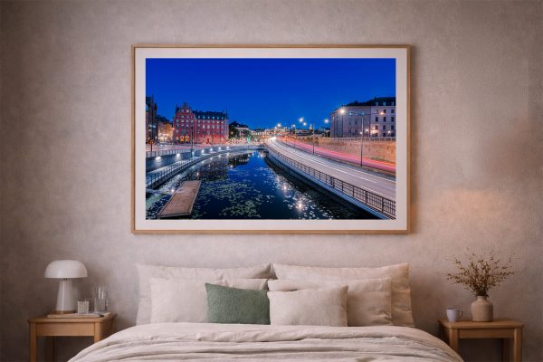 Fotografie eines beleuchteten Stadtkanals mit Straßenlichtspuren bei Nacht, als großes gerahmtes Wandbild über einem Bett im Schlafzimmer
