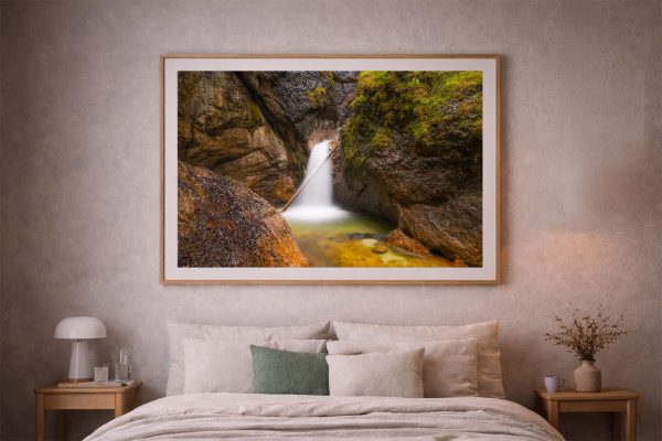 Großformatiger Fotokunstdruck eines sanften Wasserfalls in einer Felsenschlucht über einem gemütlichen Bett im Schlafzimmer.