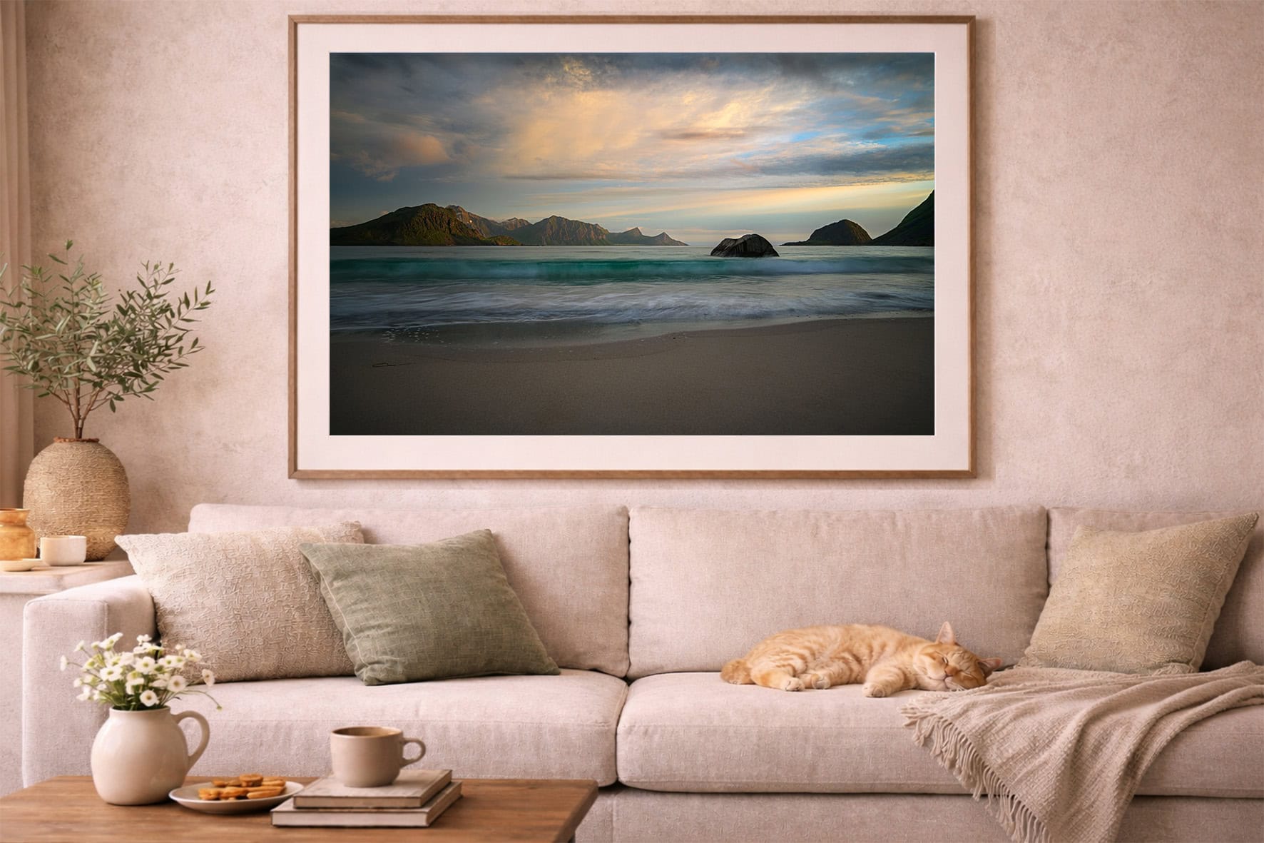 Fotografie eines ruhigen Strandes mit Bergen im Abendlicht in hellem Rahmen über beigem Sofa im Wohnzimmer