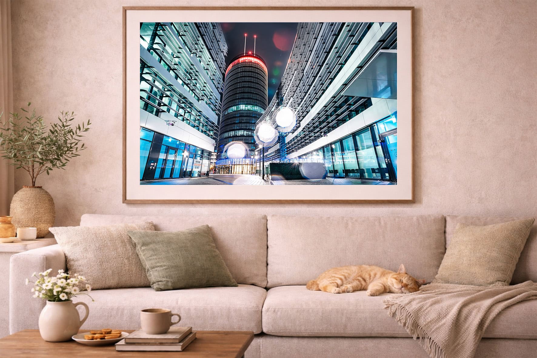 Großformatiges Foto moderner Stadtarchitektur bei Nacht über beigem Sofa mit Kissen und schlafender Katze im Wohnzimmer