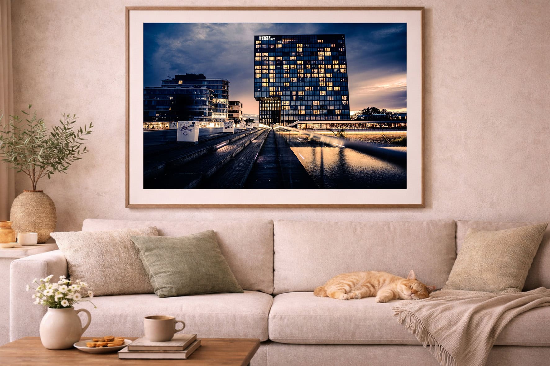 Fotografie eines beleuchteten Hochhauses bei Abenddämmerung über Wasser, als gerahmtes Wandbild über einem Sofa im Wohnzimmer