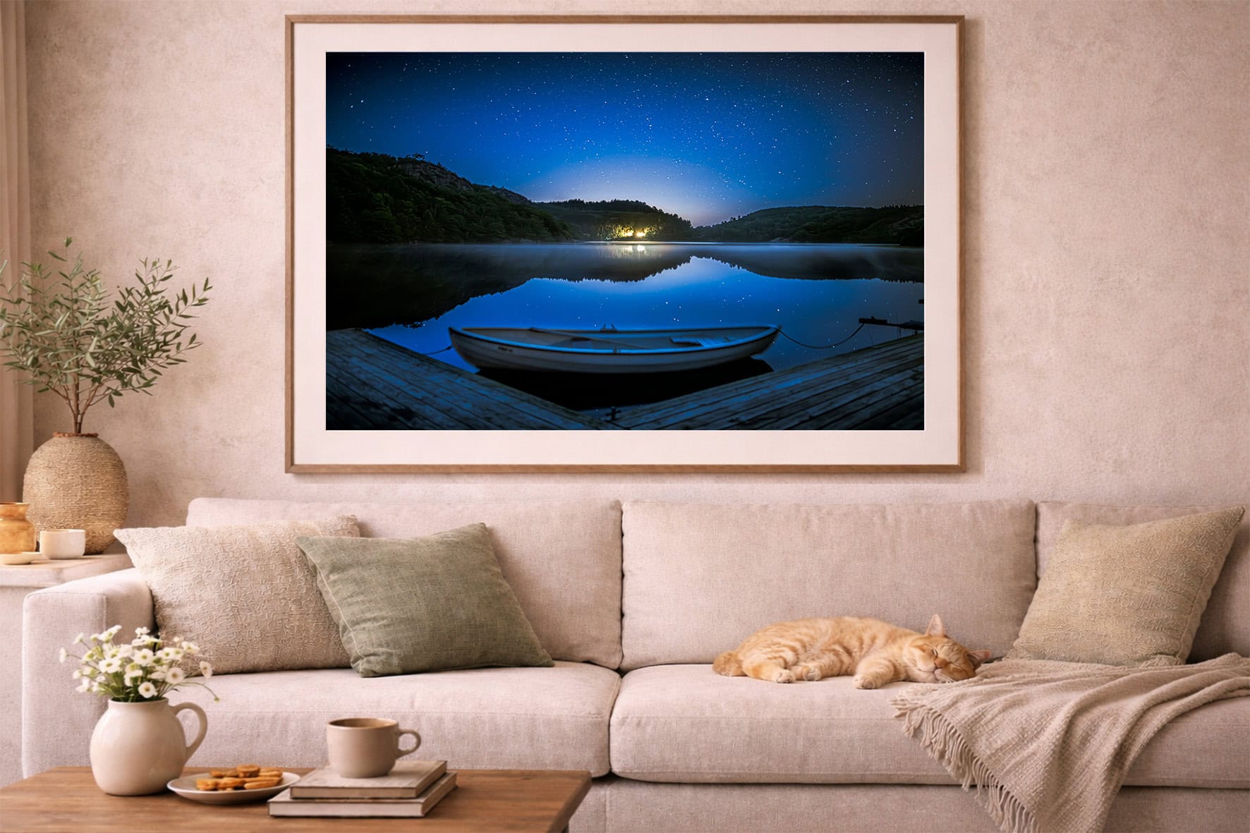 Fotografie eines Ruderboots an einem nächtlichen See mit Sternenhimmel, gerahmt über einem beigen Sofa im gemütlichen Wohnzimmer