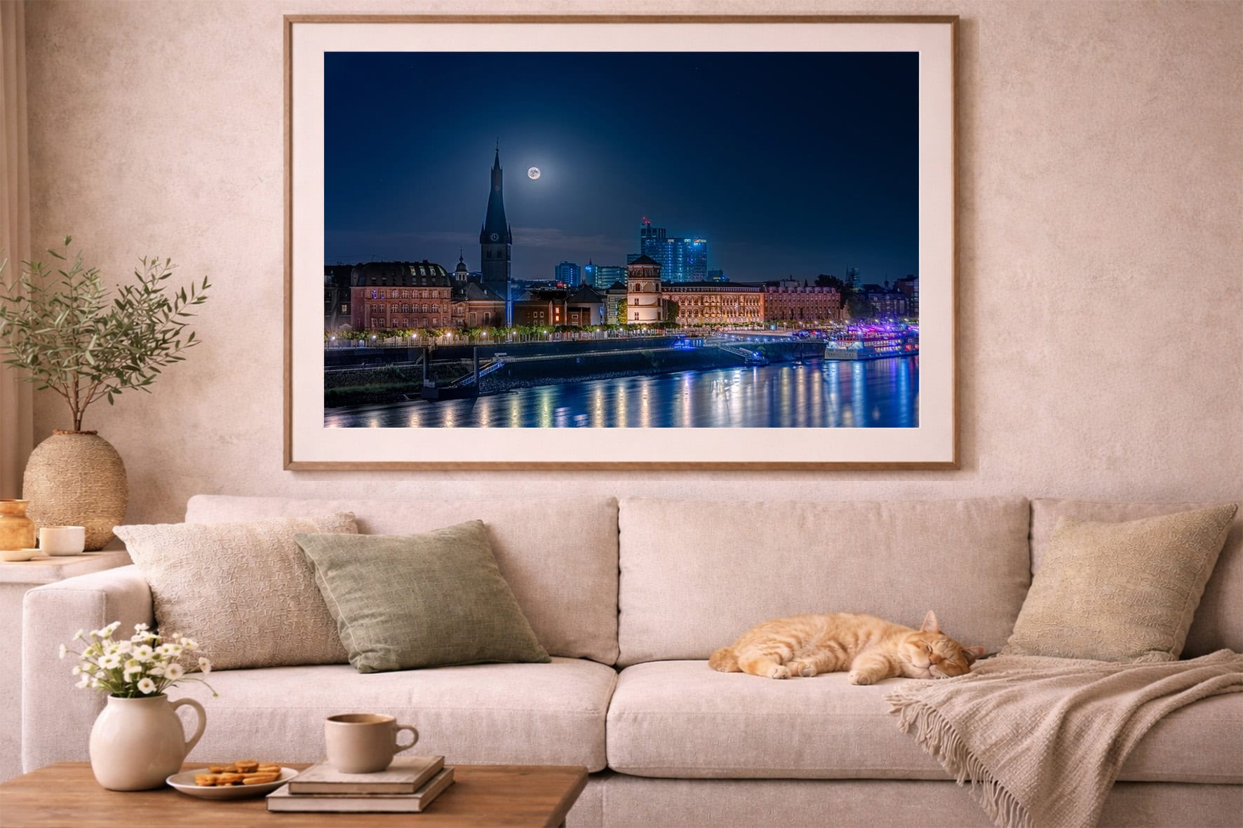 Großes Wandbild über Sofa zeigt nächtliche Stadtansicht am Fluss mit Vollmond, beleuchteten Gebäuden und Reflexionen im Wasser.