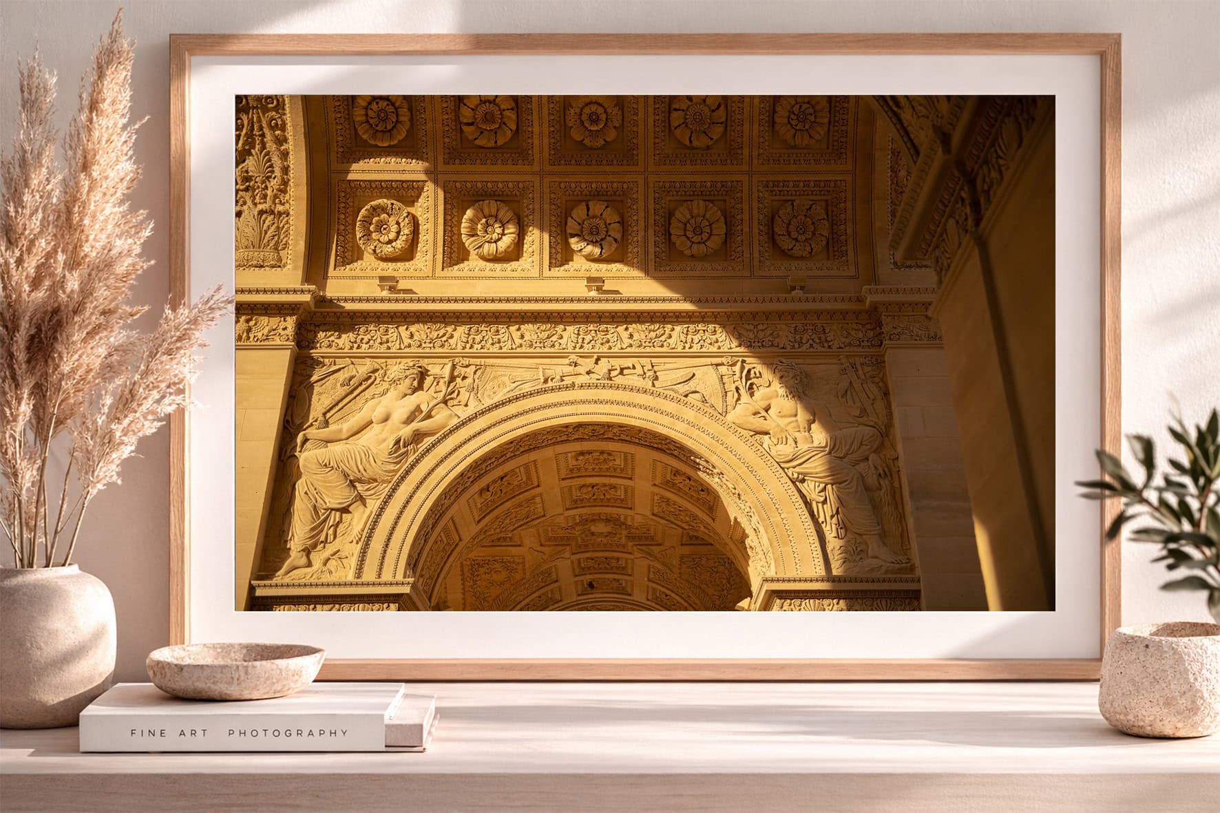Fotografie eines reich verzierten Steinbogens mit Figurenreliefs im goldenen Licht, gerahmt auf einem Sideboard mit Dekoobjekten