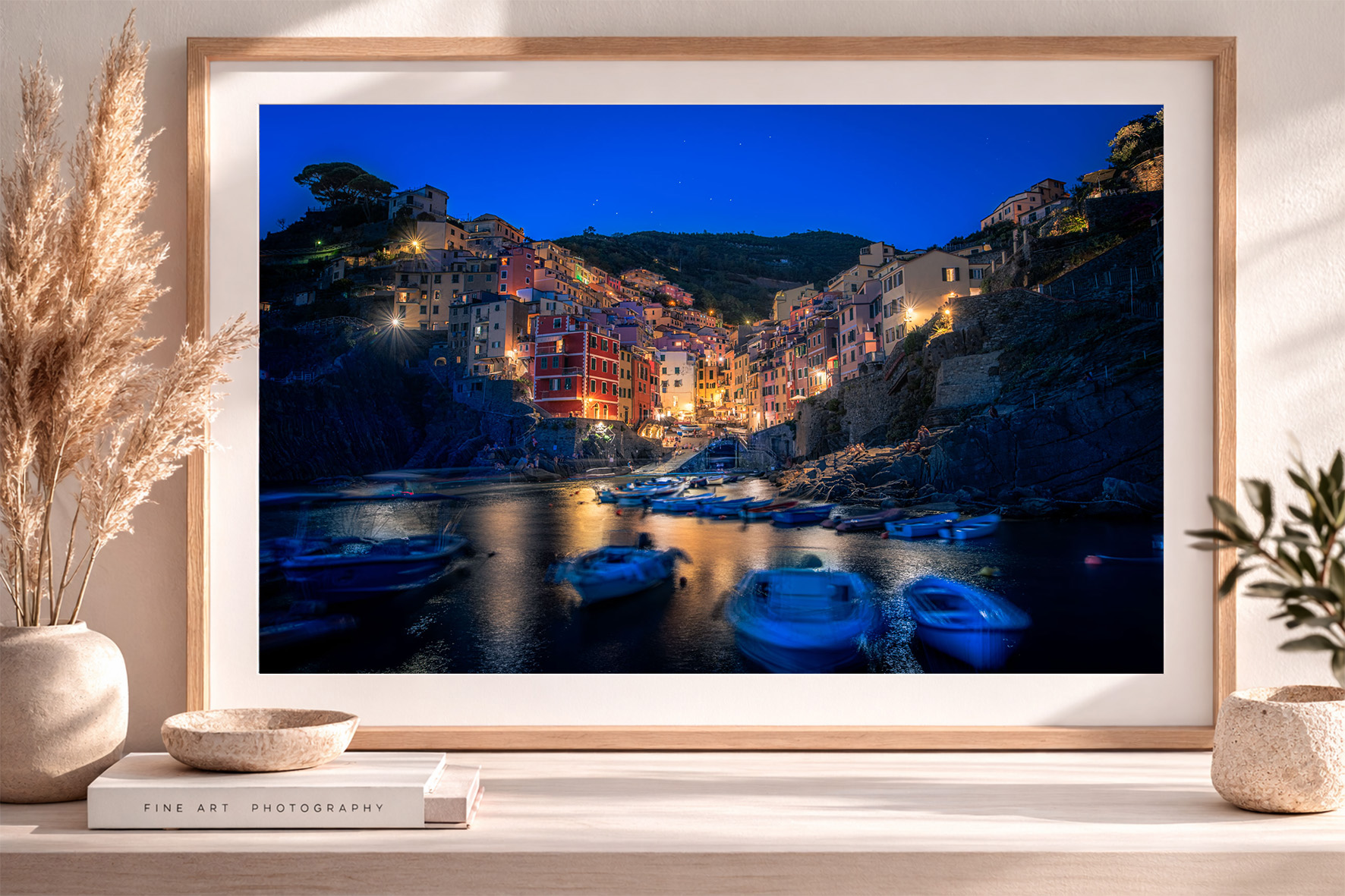 Fotografie eines mediterranen Küstenortes bei Nacht mit beleuchteten Häusern und Booten im Hafen, gerahmt im modernen Interior