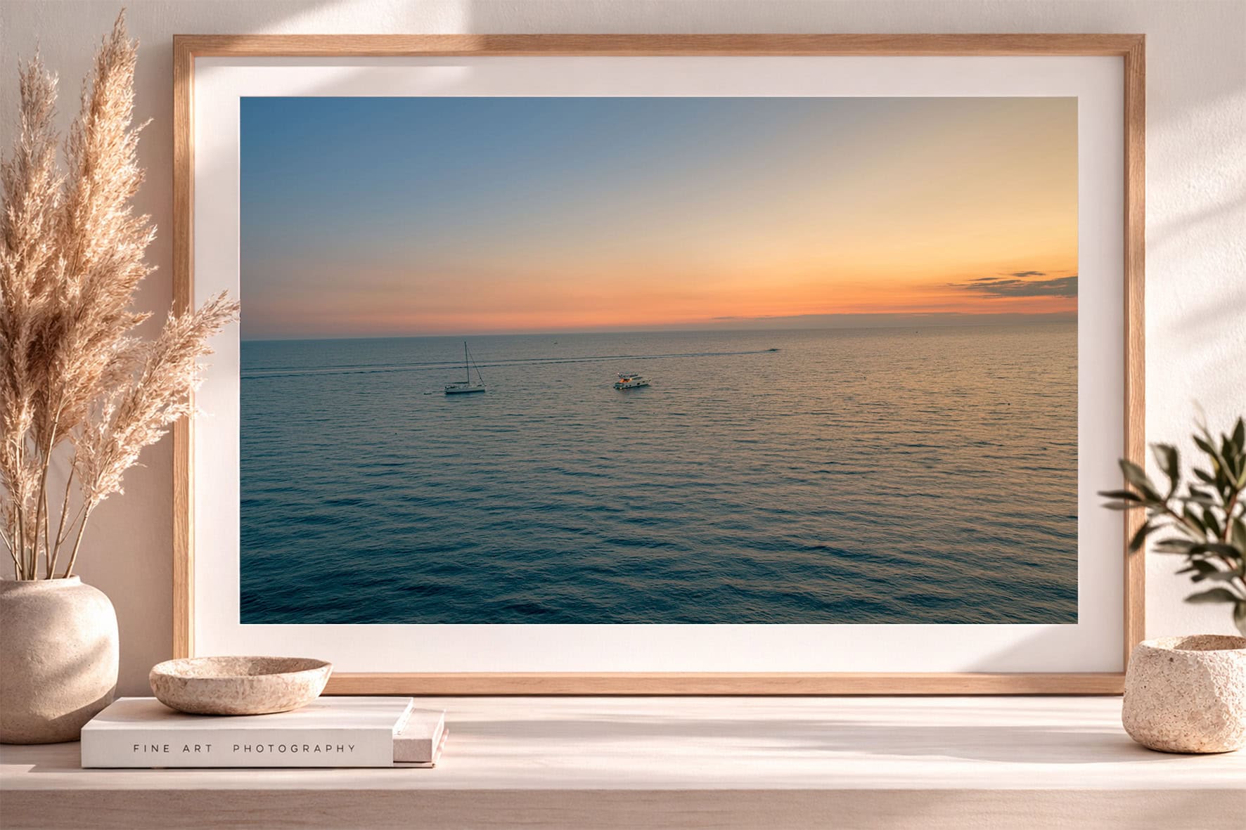 Gerahmtes Foto mit zwei Booten auf ruhigem Meer bei warmem Sonnenuntergang, auf Sideboard mit Vasen und Büchern dekoriert
