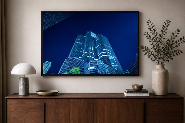 Fotografie eines beleuchteten Hochhauses bei Nacht in schwarzem Rahmen über Sideboard im modernen Wohnzimmer
