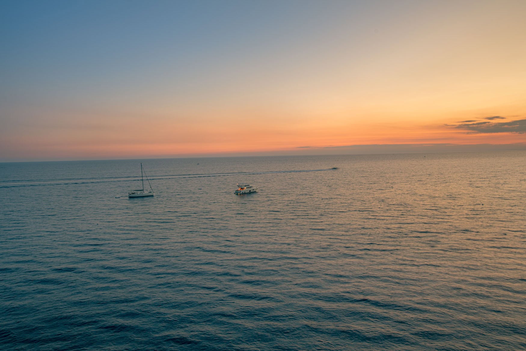 Ruhige Meeresfläche bei Manarola mit zwei Booten unter orange-blauem Abendhimmel