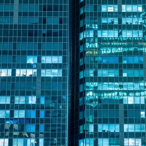 Glasfassaden von Hochhäusern in La Défense Paris bei Nacht mit blauen Spiegelungen und beleuchteten Fenstern