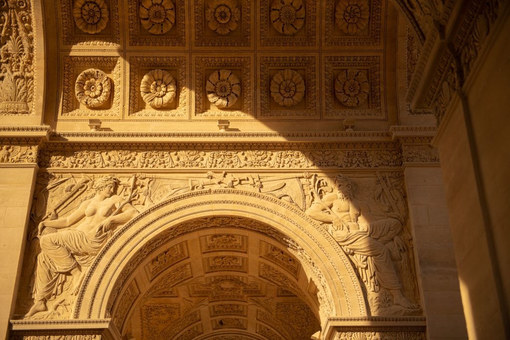 Detailansicht des Arc de Triomphe du Carrousel in Paris mit Reliefs und Rosetten im warmen Sonnenuntergang