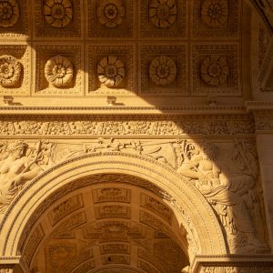 Detailansicht des Arc de Triomphe du Carrousel in Paris mit Reliefs und Rosetten im warmen Sonnenuntergang