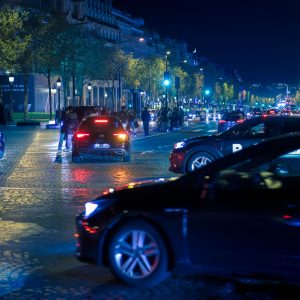 Nachtverkehr in Paris auf breiter Allee mit Autos, Bäumen, Straßenlaternen und leuchtender Fahrbahn