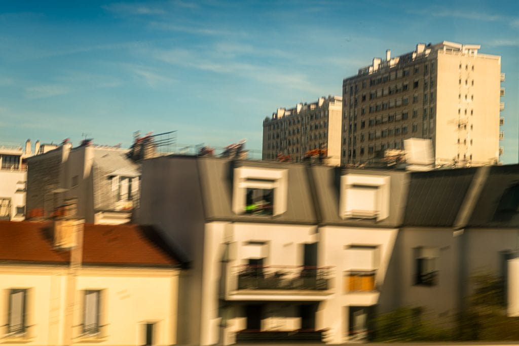 Unscharfe Häuserdächer und Wohnblöcke in Asnières bei Paris mit bewegter Ansicht unter blauem Himmel