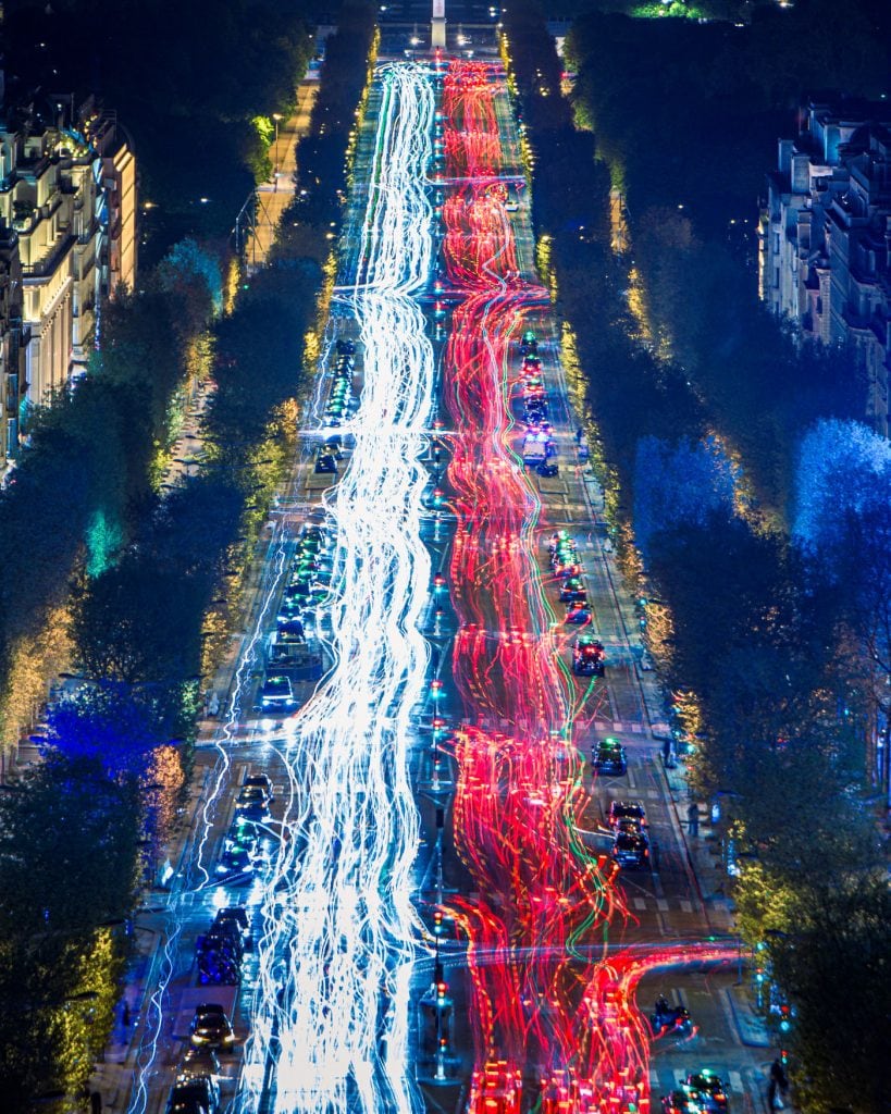 Blick auf die Champs-Élysées in Paris mit roten und weißen Lichtspuren bei Nacht