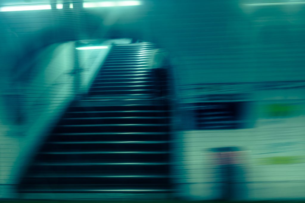 Bewegungsunscharfe Treppe in einer Pariser Metrostation mit kühlen Lichtstreifen und gefliesten Wänden