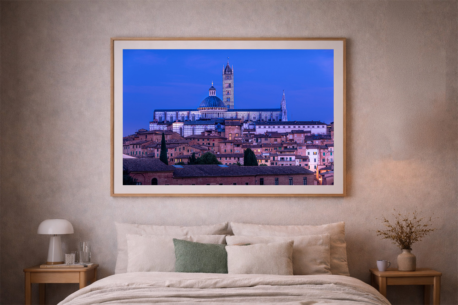 Fotografie einer historischen Stadt mit beleuchtetem Dom bei blauem Abendhimmel, als gerahmtes Wandbild über einem Bett in einem gemütlichen Schlafzimmer