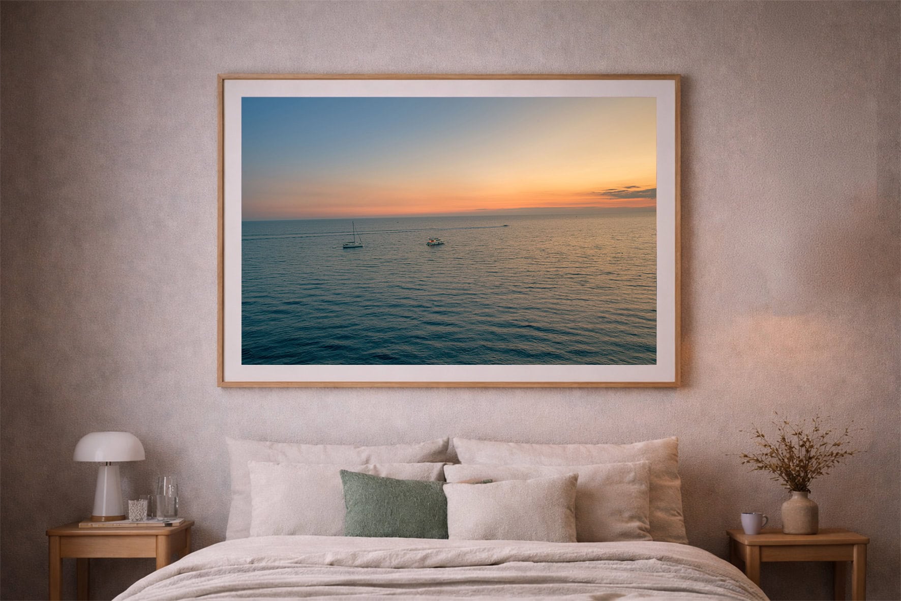 Großer gerahmter Fotokunstdruck mit ruhigem Meer und Booten im Sonnenuntergang über einem Bett in einem dezenten Schlafzimmer.