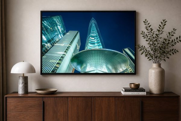 Fotografie von beleuchteten Hochhäusern bei Nacht in Nahaufnahme, als gerahmtes Wandbild über einem Sideboard im modernen Wohnraum.