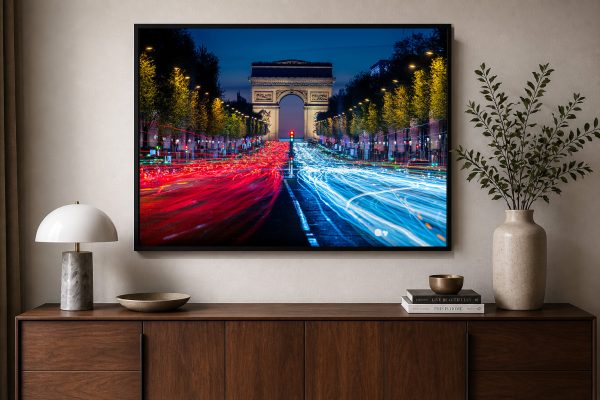 Fotografie eines nächtlichen Boulevards mit Lichtspuren vor einem Triumphbogen, gerahmt über einem Holzsideboard im modernen Wohnzimmer.