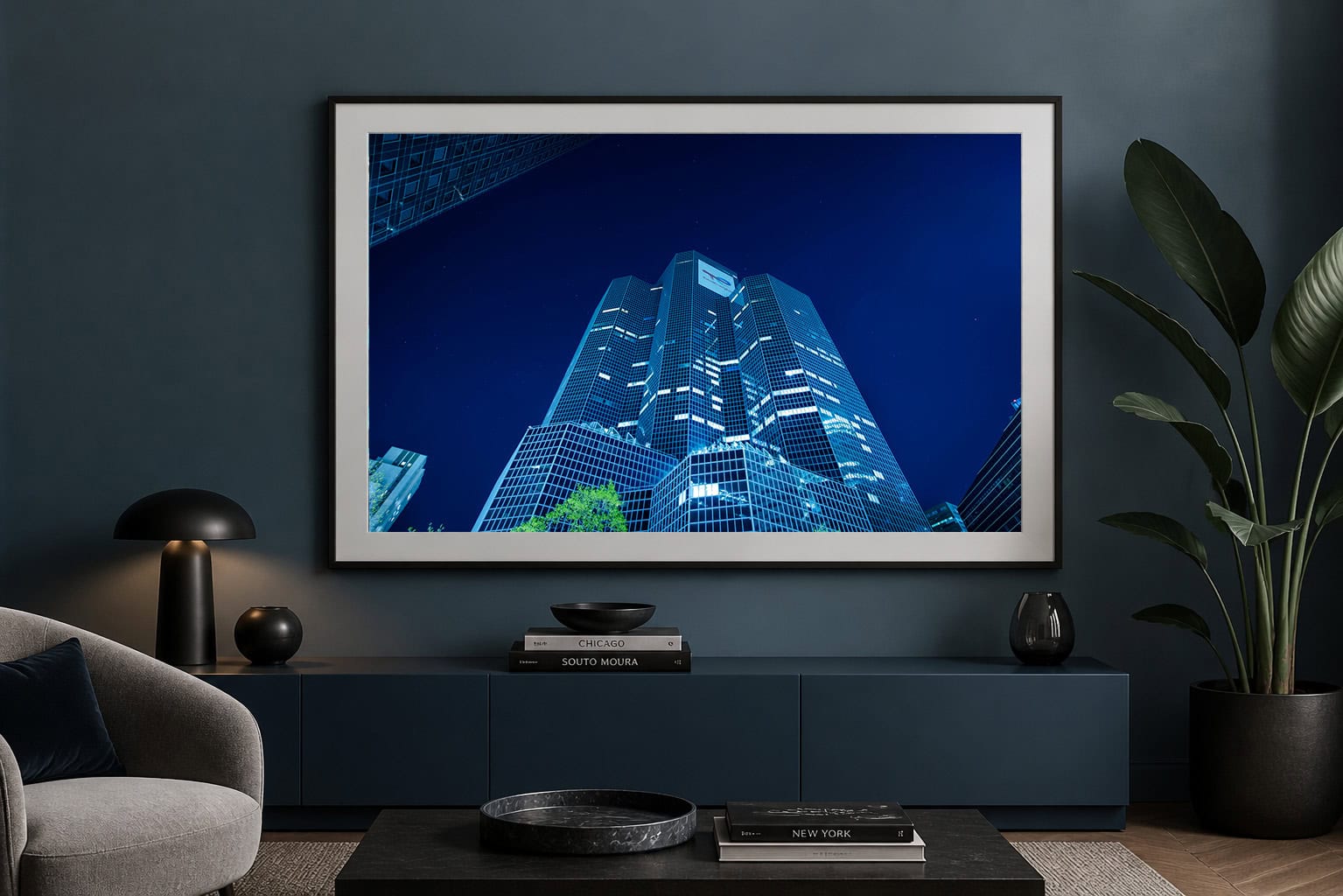 Fotografie eines beleuchteten Hochhauses bei Nacht, im Wohnzimmer über einem dunkelblauen Sideboard gerahmt