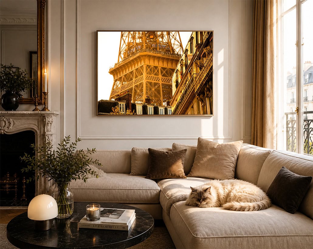 Fotografie eines goldenen Eiffelturmdetails über einem beigen Sofa mit Katze in einem hellen Wohnzimmer