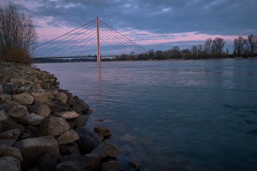 Fleherbrücke bei Düsseldorf in der Dämmerung über dem Rhein mit Ufersteinen