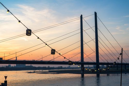 Rheinkniebrücke in Düsseldorf bei Sonnenuntergang mit Lichterkette am Rheinufer