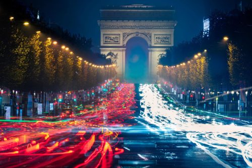 Arc de Triomphe in Paris bei Nacht mit roten und weißen Lichtspuren auf den Champs-Élysées